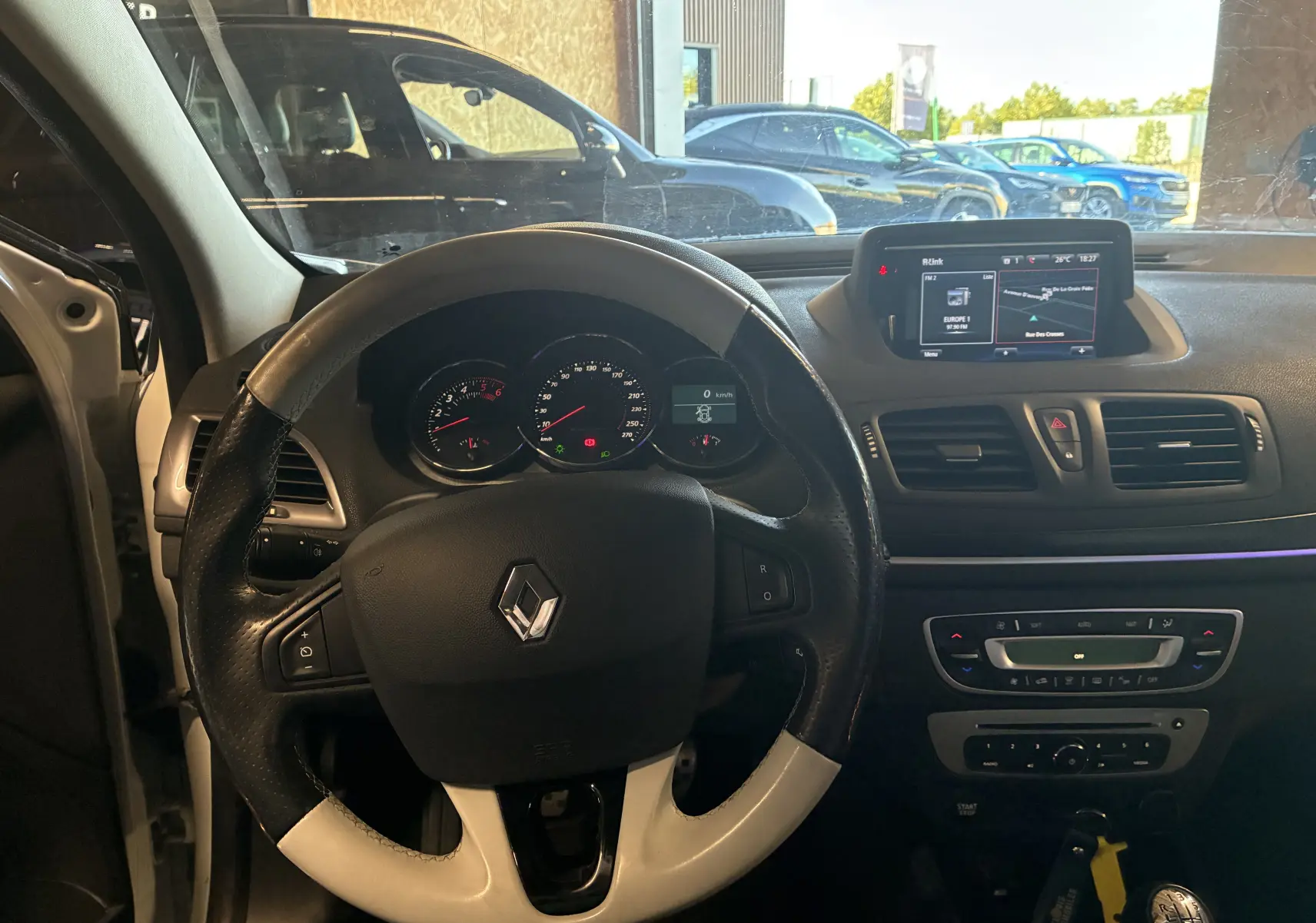 Vue intérieure du tableau de bord et volant cuir bi-ton noir et blanc de la Renault Mégane Coupé 2.0 DCI 165 GT de 2014.