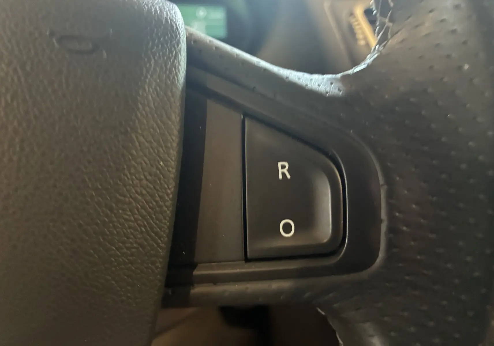 Gros plan sur les boutons R et O du volant cuir noir de la Renault Mégane Coupé 2.0 DCI 165 GT de 2014.