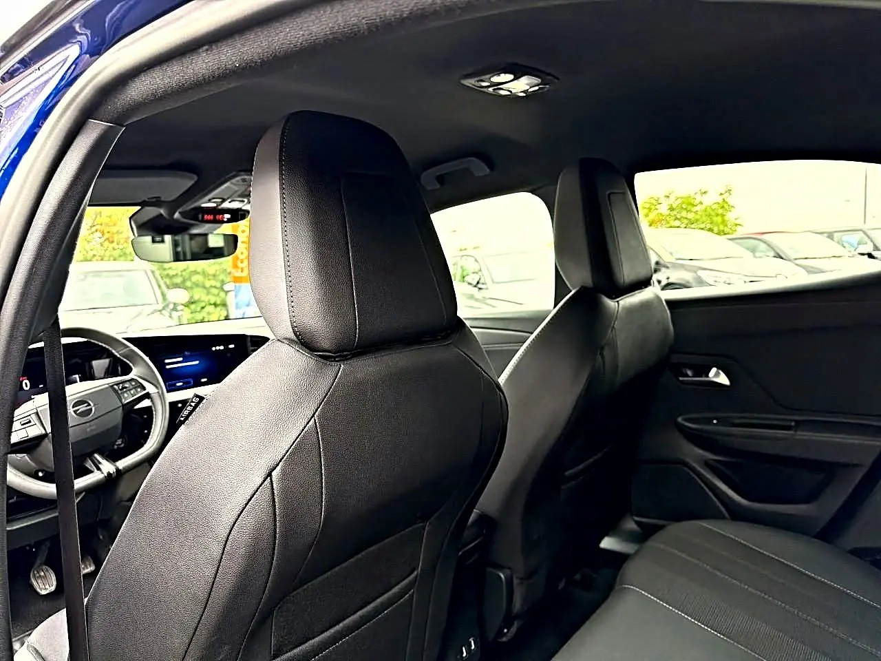 Vue intérieure arrière de l'Opel Mokka bleu 2025, montrant les sièges avant en cuir noir et le tableau de bord digital.