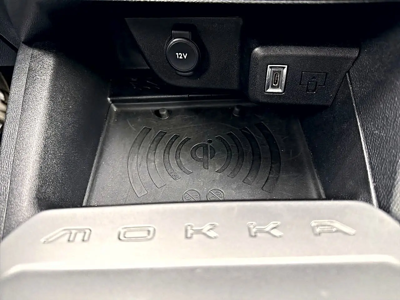 Gros plan sur le compartiment de chargement sans fil et prises USB/12V dans l'habitacle noir de l'Opel Mokka.