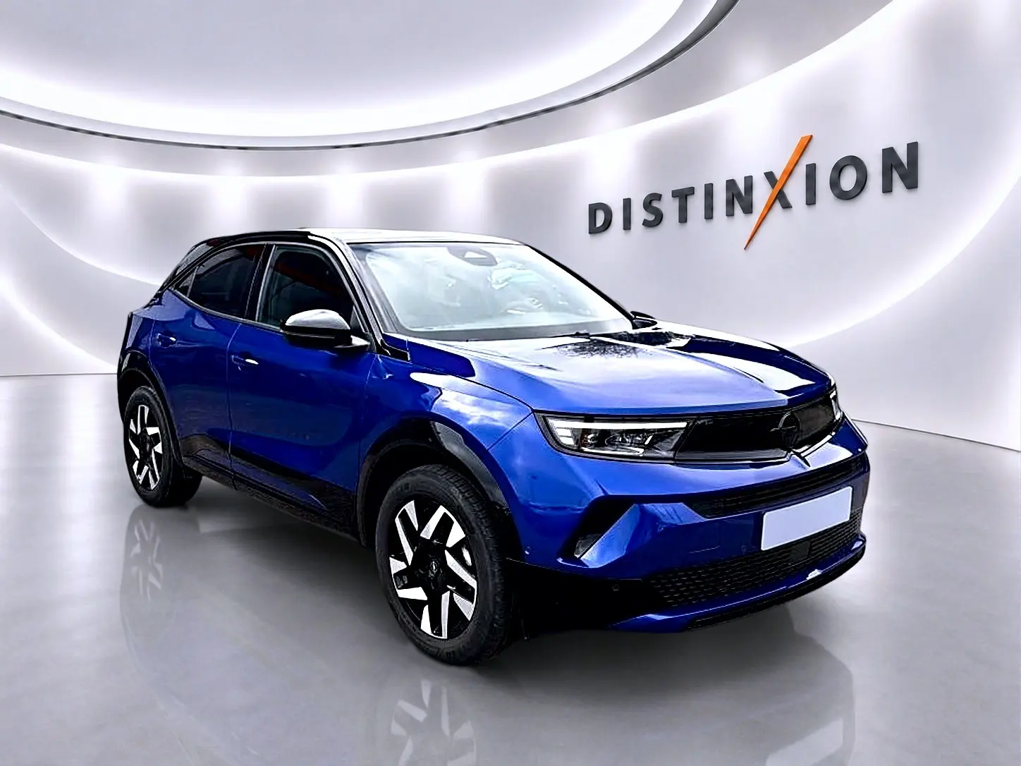 Opel Mokka 1.2 turbo bleu en 3/4 avant droit, avec jantes noires et blanches, dans un showroom lumineux.