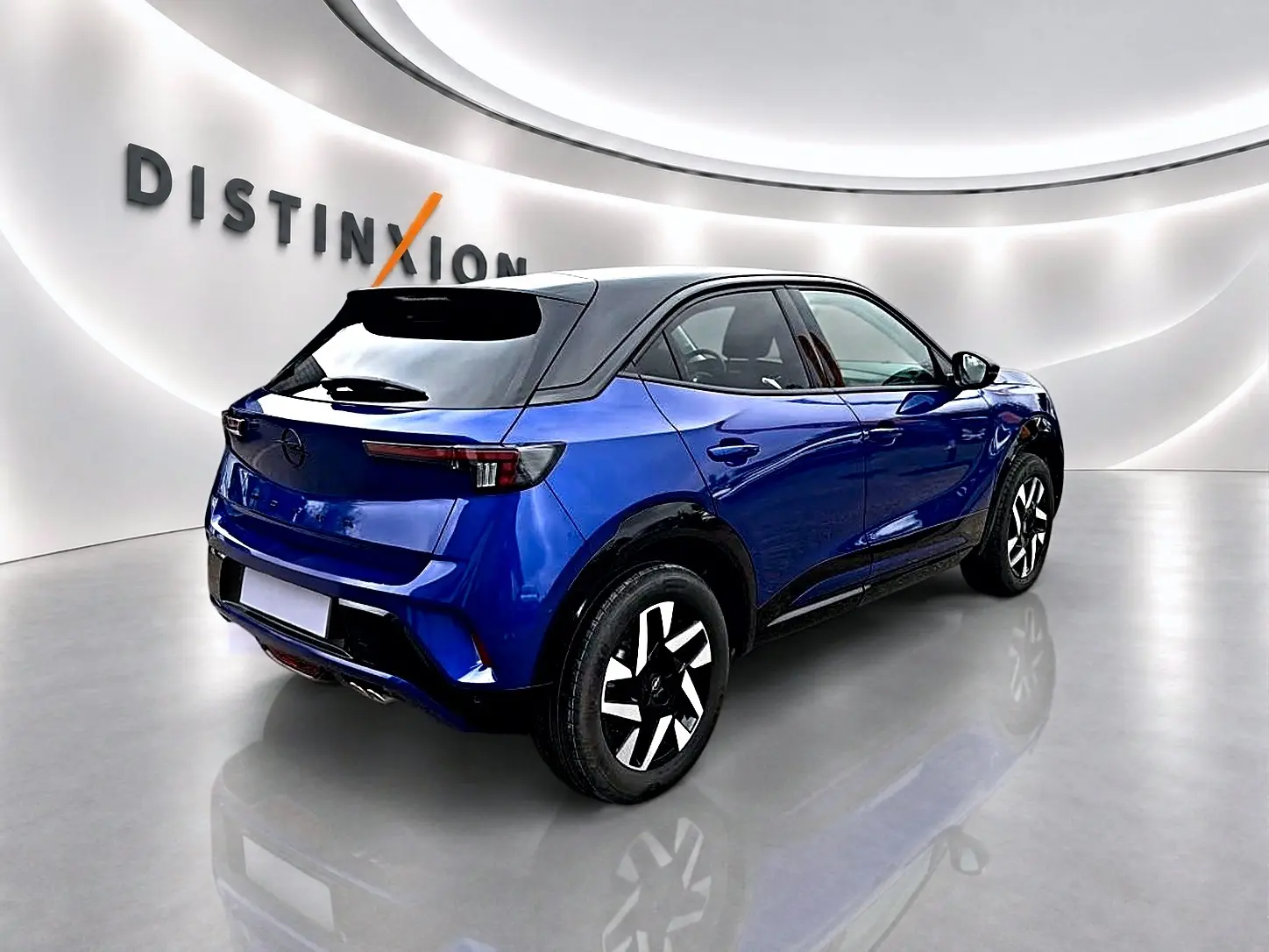 Vue 3/4 arrière droite d'un Opel Mokka bleu avec toit noir, dans un showroom lumineux au sol brillant.