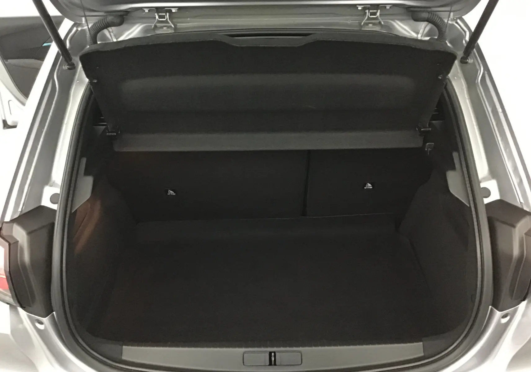 Coffre ouvert vu de l'arrière d'une Peugeot 208 gris artense, montrant l'espace de chargement vide et la trappe arrière.