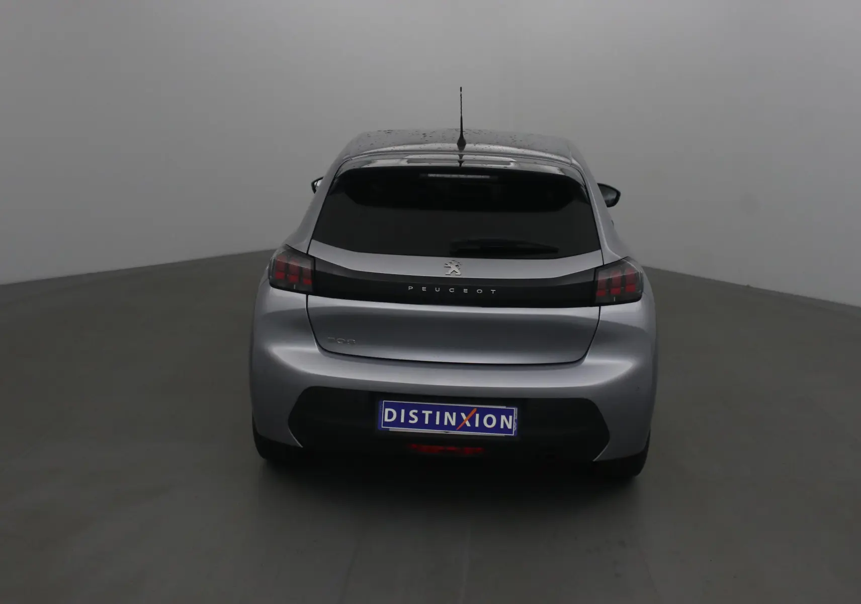 Vue arrière d'une Peugeot 208 gris Artense 2022 avec feux arrière noirs et lunette arrière teintée.