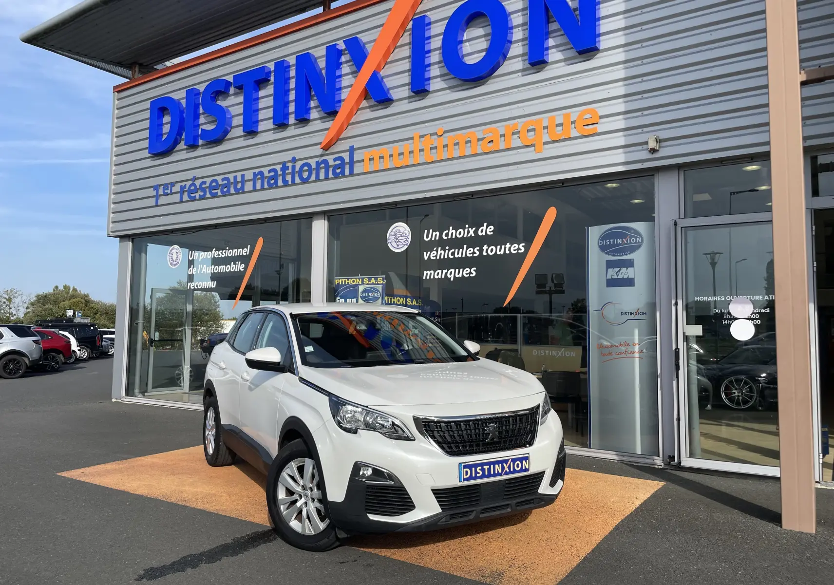 Peugeot 3008 blanc en 3/4 avant droit devant un showroom Distinxion avec calandre noire et jantes argentées.
