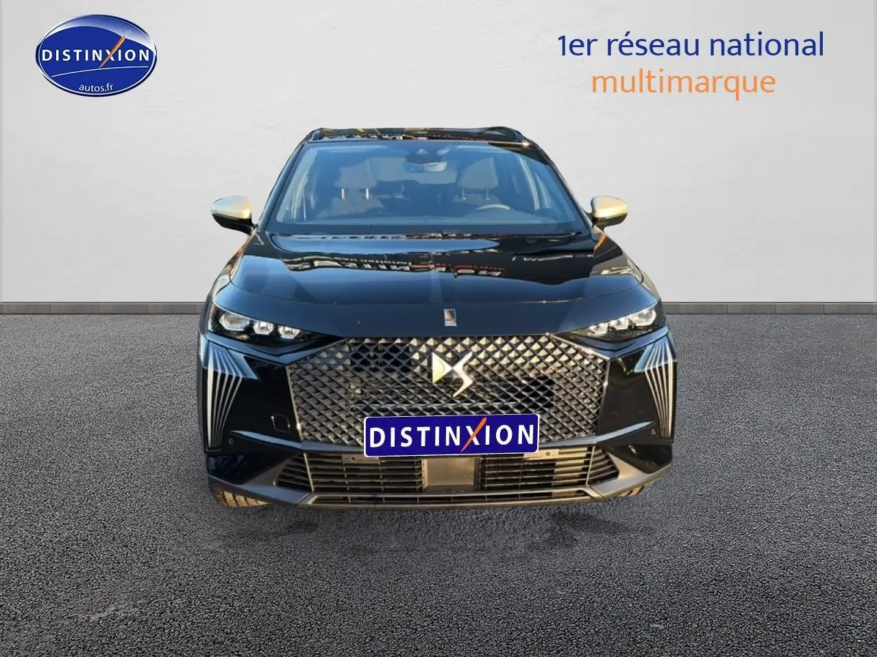 Vue frontale d'un DS7 noir avec calandre distinctive et phares LED fins, sur fond neutre avec logo Distinxion.