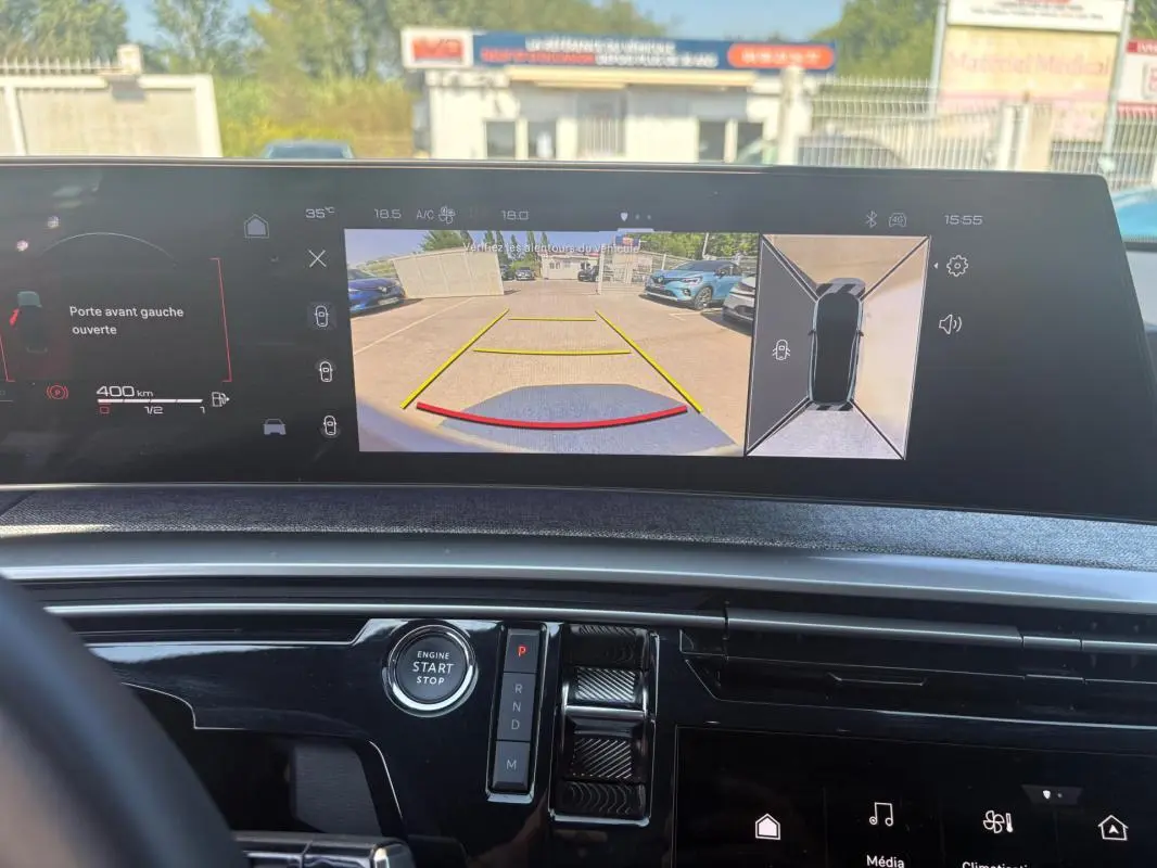 Vue intérieure du tableau de bord du Peugeot 3008 Hybrid gris 2025, écran affichant la caméra de recul et les alertes portes ouvertes.