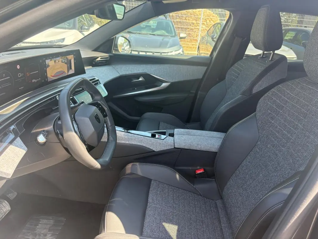 Vue intérieure côté conducteur du Peugeot 3008 Hybrid 145 e-DCS6 Allure 2025, sièges gris et tableau de bord numérique.