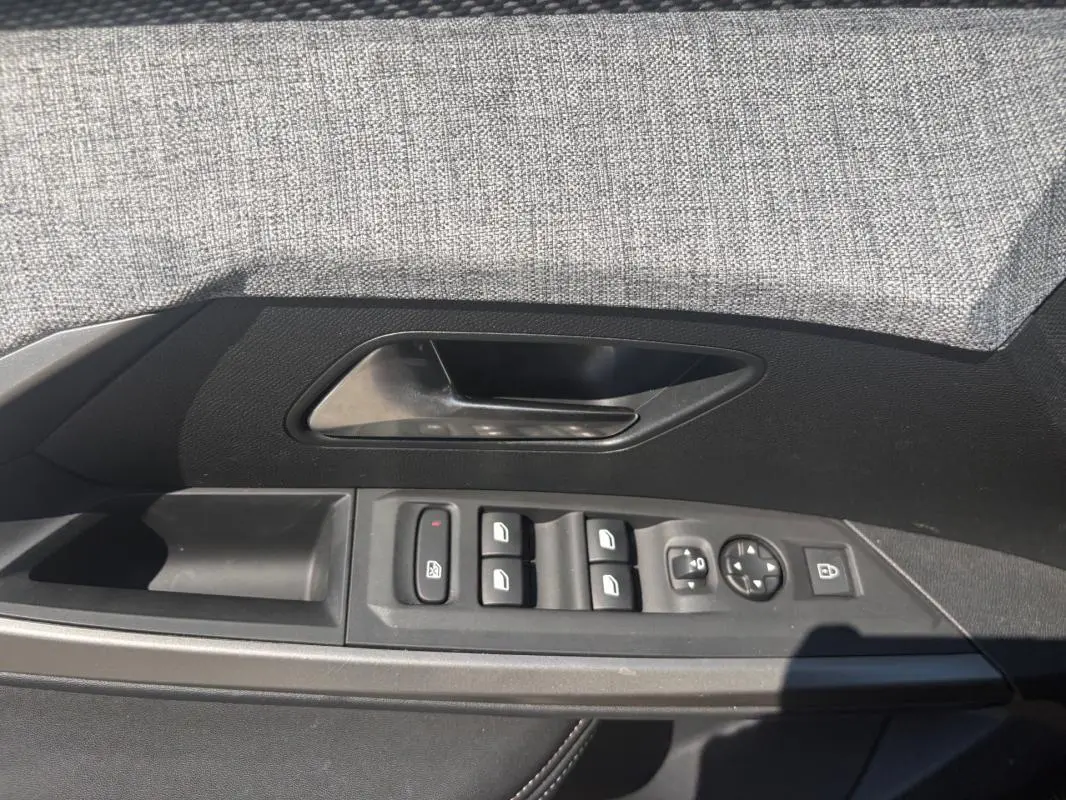 Vue rapprochée de la porte côté gauche du Peugeot 3008 gris, montrant les commandes des vitres et rétroviseurs.