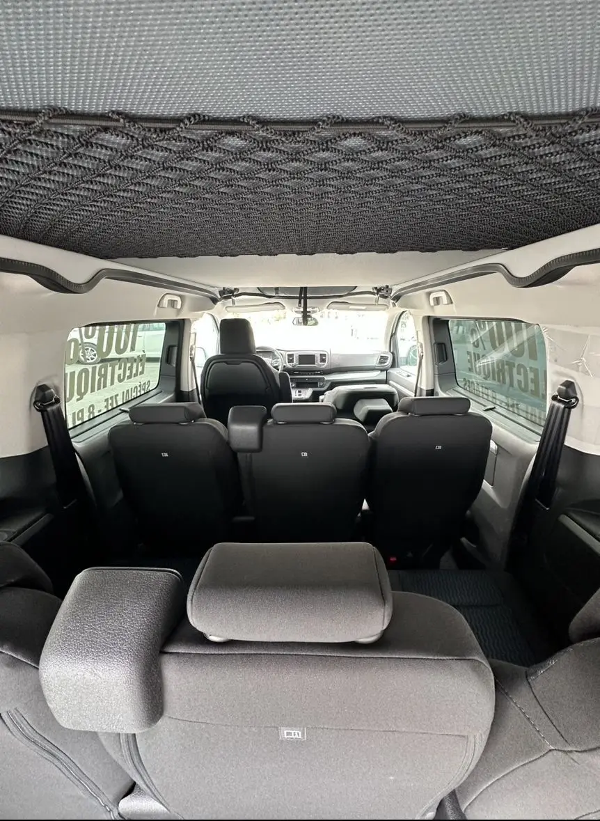 Vue intérieure arrière du Citroën Jumpy van blanc, montrant les sièges noirs et le tableau de bord à l'avant.