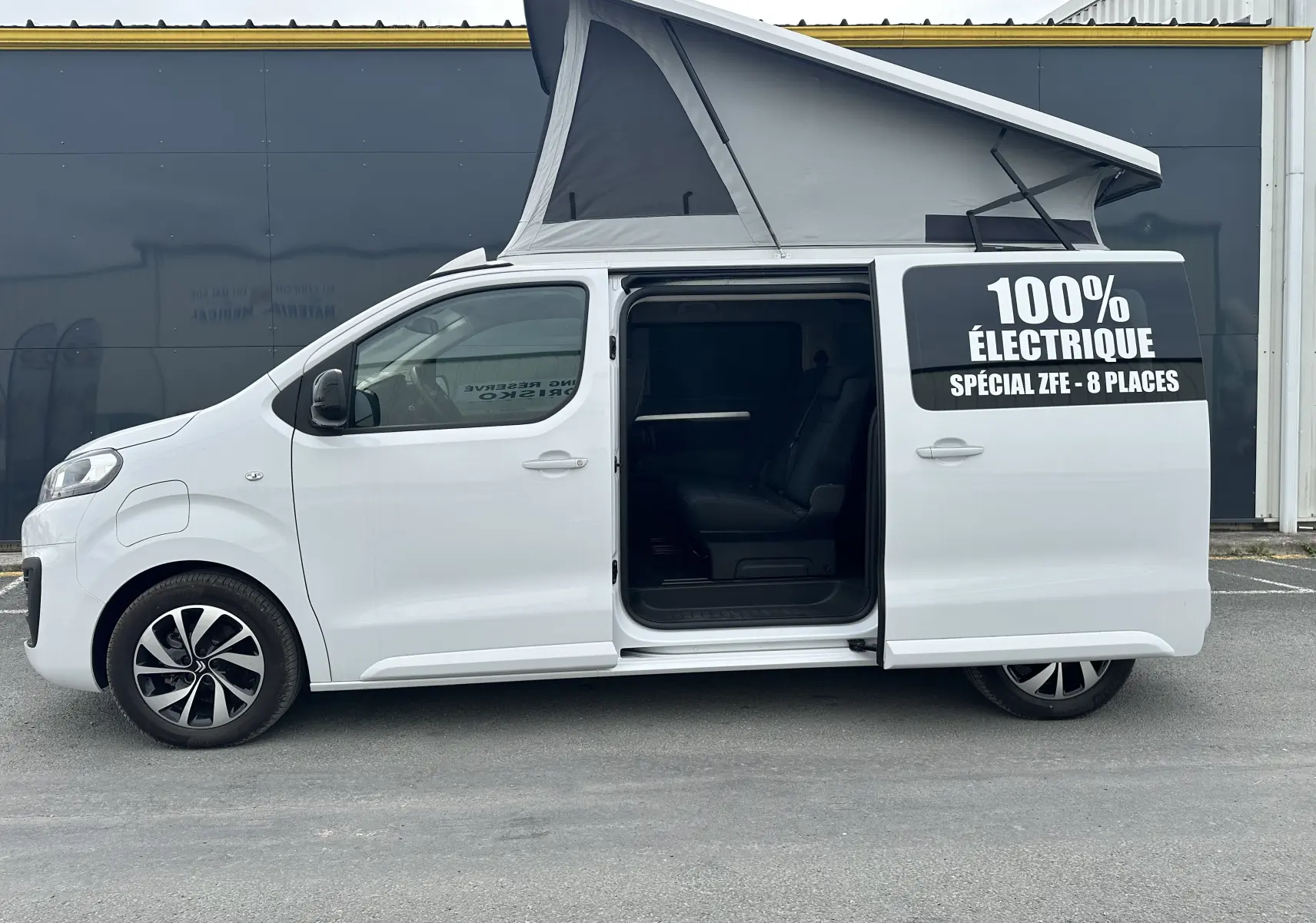 Profil gauche d'un Citroën Jumpy van blanc électrique avec porte coulissante ouverte et toit relevable gris.