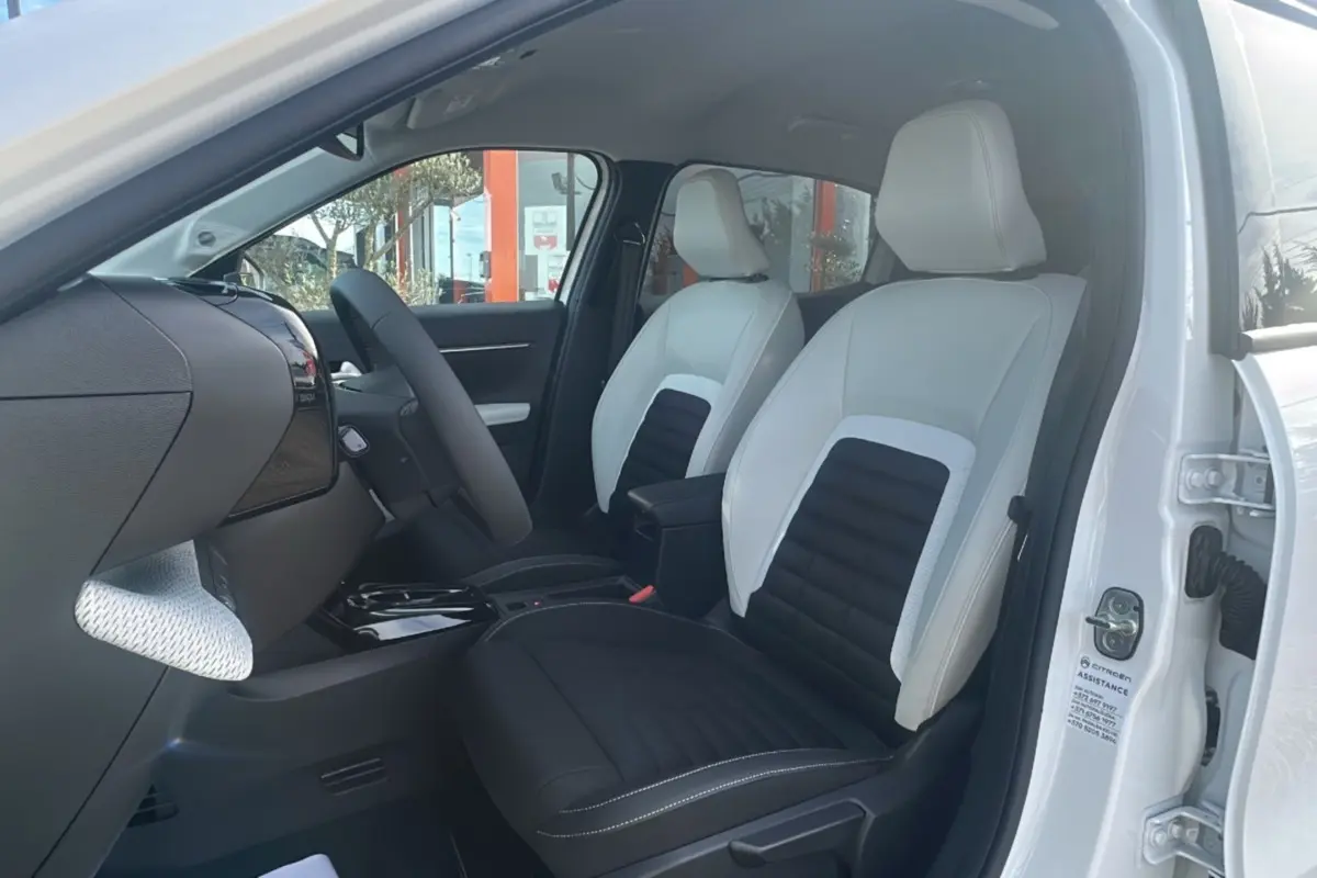 Vue intérieure côté conducteur du Citroën C3 Aircross blanc banquise, sièges tissu bicolores avec accoudoir central.