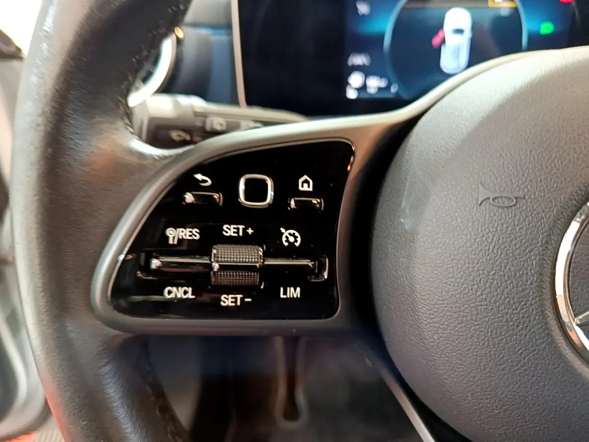 Gros plan sur les commandes à gauche du volant cuir d'une Mercedes Classe A 180 d Business Line 2020.