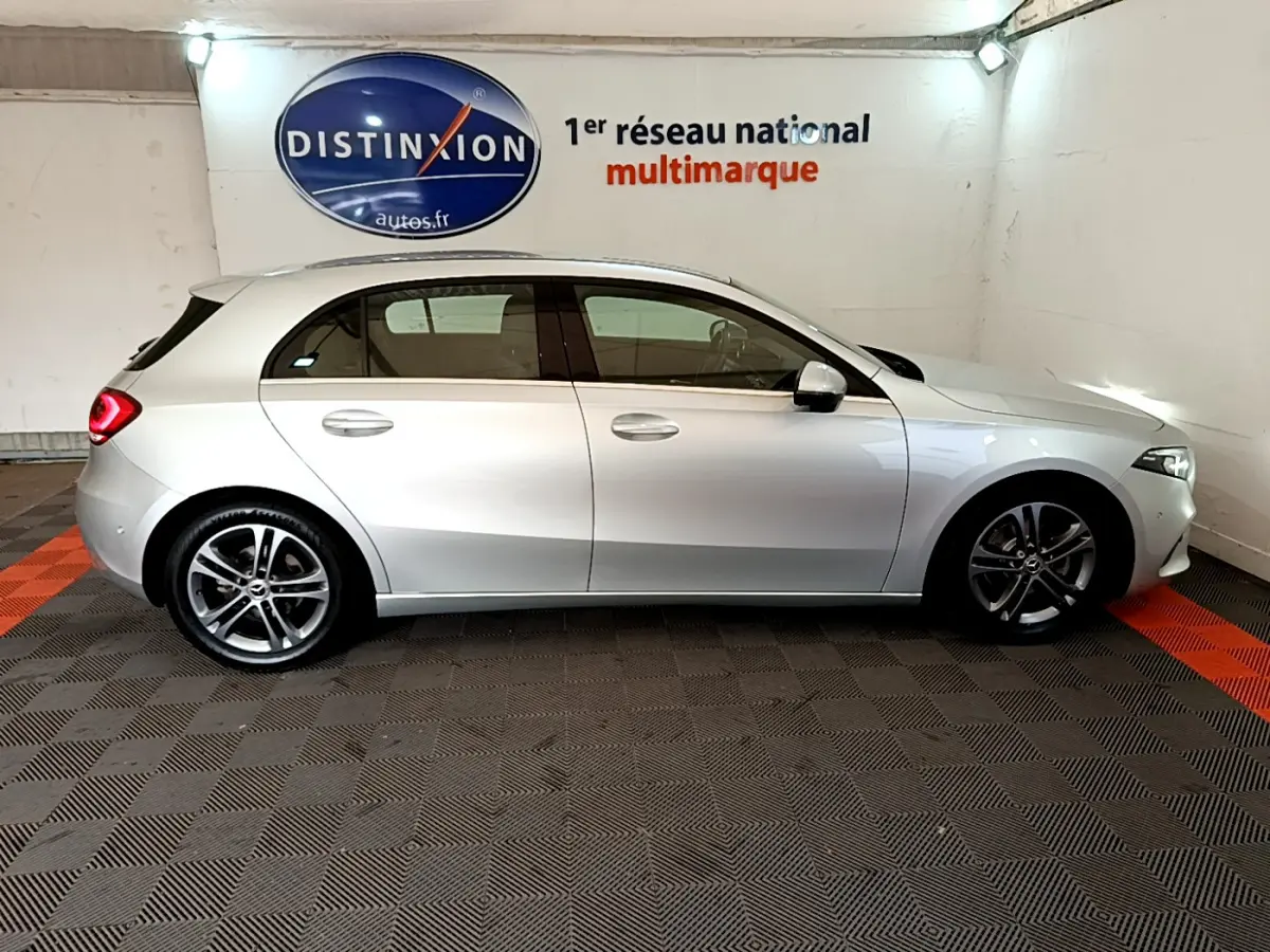 Profil côté droit d'une Mercedes Classe A gris clair 2020 garée en intérieur sur sol à damier noir et rouge.