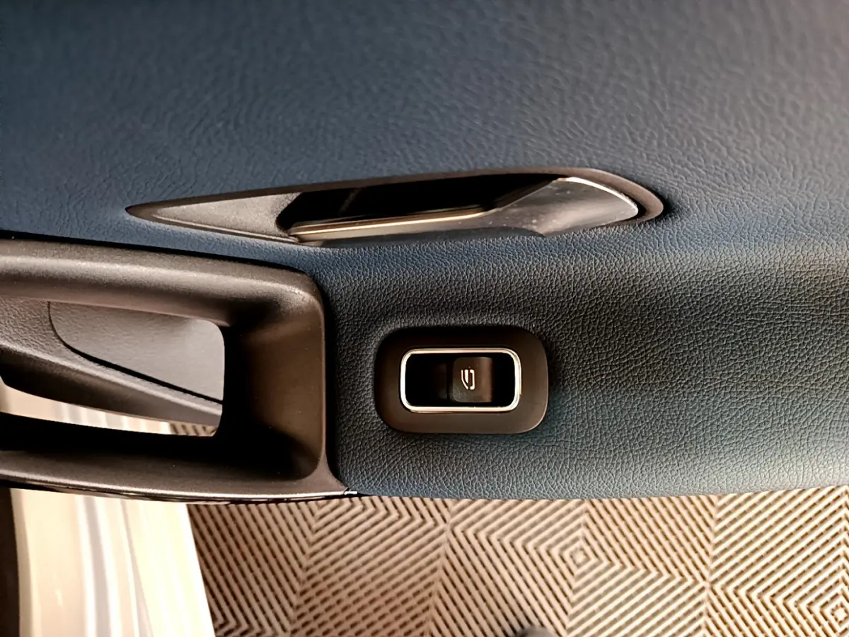 Gros plan sur la poignée intérieure et le bouton de verrouillage de porte d'une Mercedes Classe A gris clair.