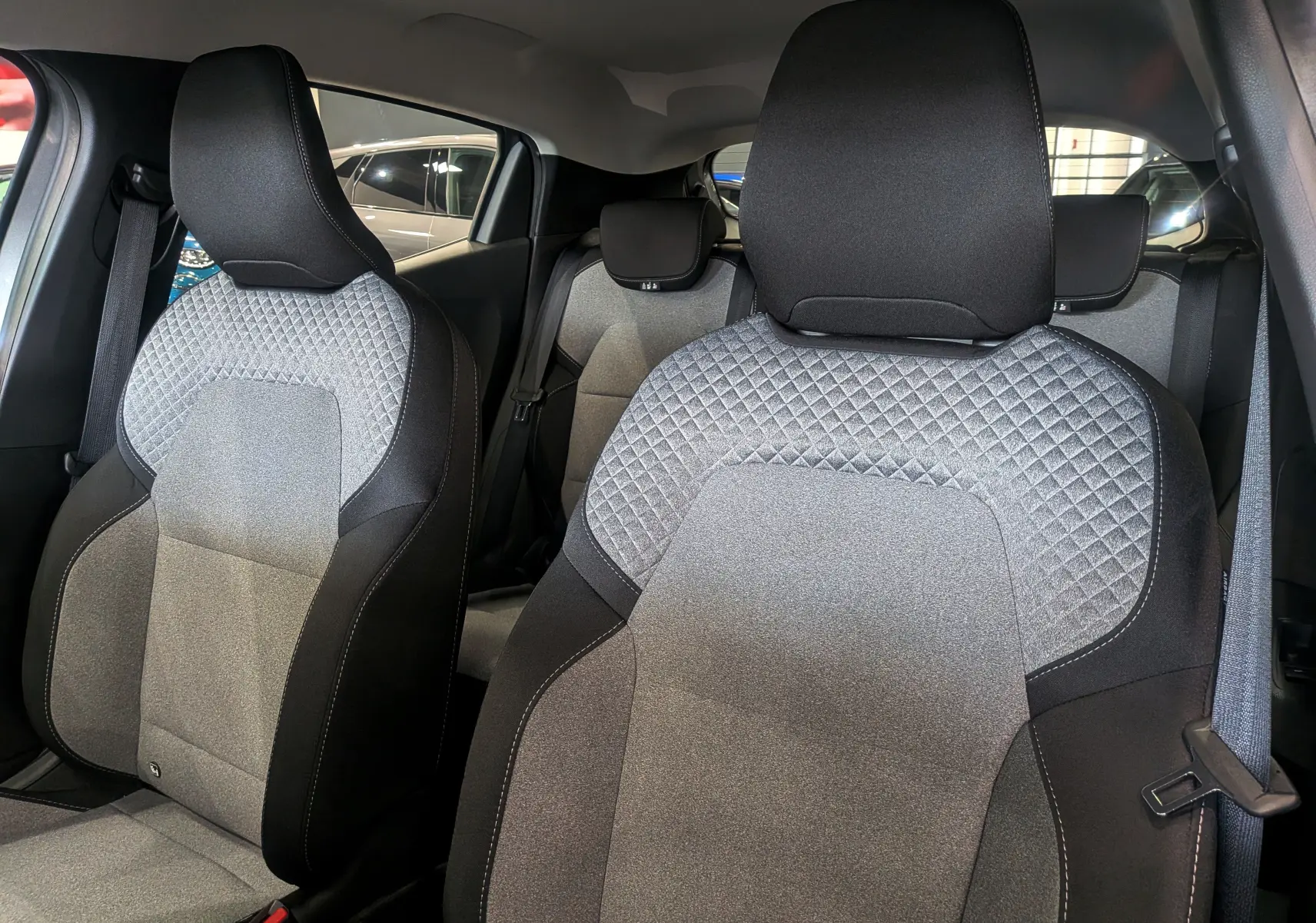 Gros plan sur les sièges avant en tissu gris et noir de la Renault Clio V Blue dCi 100 CH Evolution, intérieur moderne.