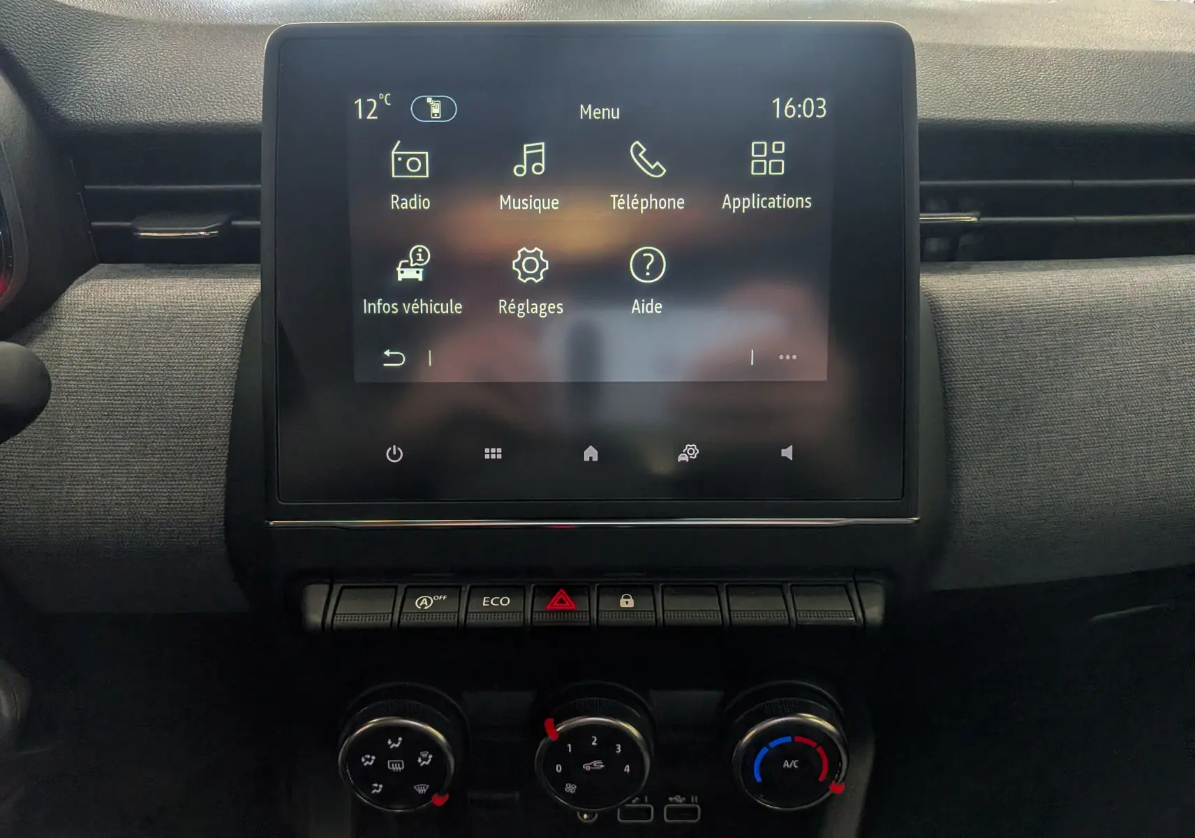 Vue rapprochée de l’écran tactile central et des commandes de climatisation de la Renault Clio V gris schiste.