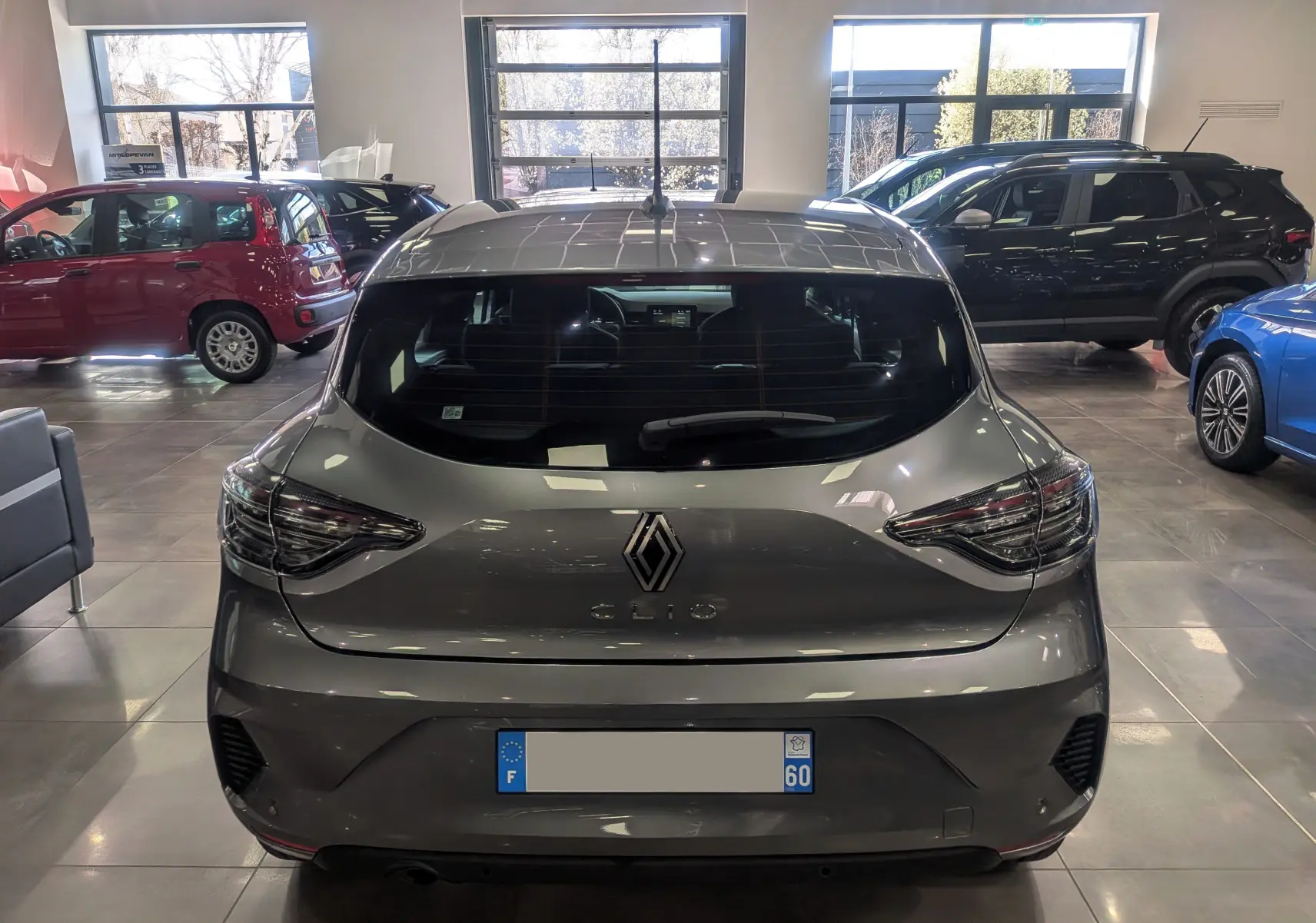 Vue arrière d'une Renault Clio V Blue dCi 100 CH Evolution gris schiste dans un showroom lumineux.