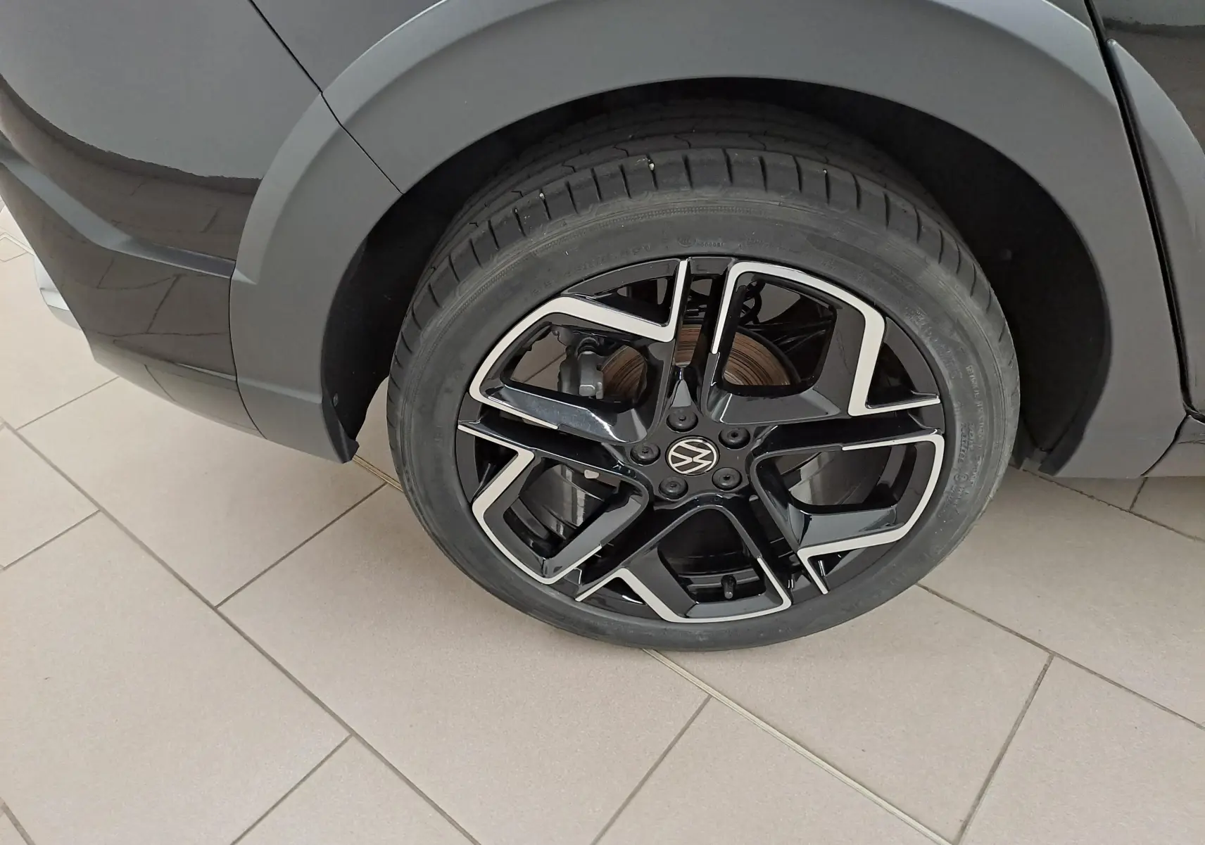 Gros plan sur la roue avant droite avec jante alliage noir et argent du Volkswagen Taigo Noir Intense nacré.