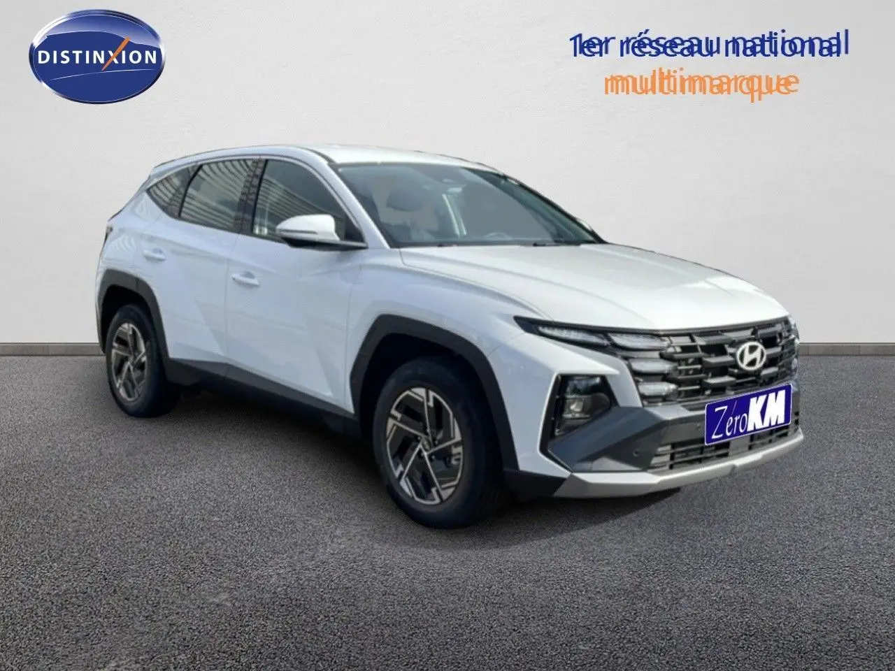 Vue 3/4 avant du Hyundai Tucson blanc Atlas avec calandre distinctive et jantes bi-ton modernes.