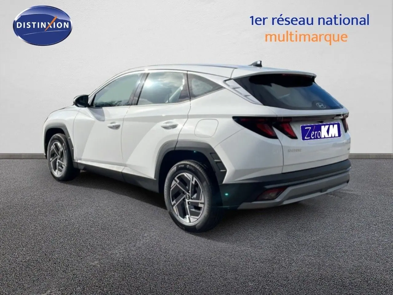 Vue 3/4 arrière droite d'un Hyundai Tucson blanc Atlas avec jantes bi-ton et vitres teintées.