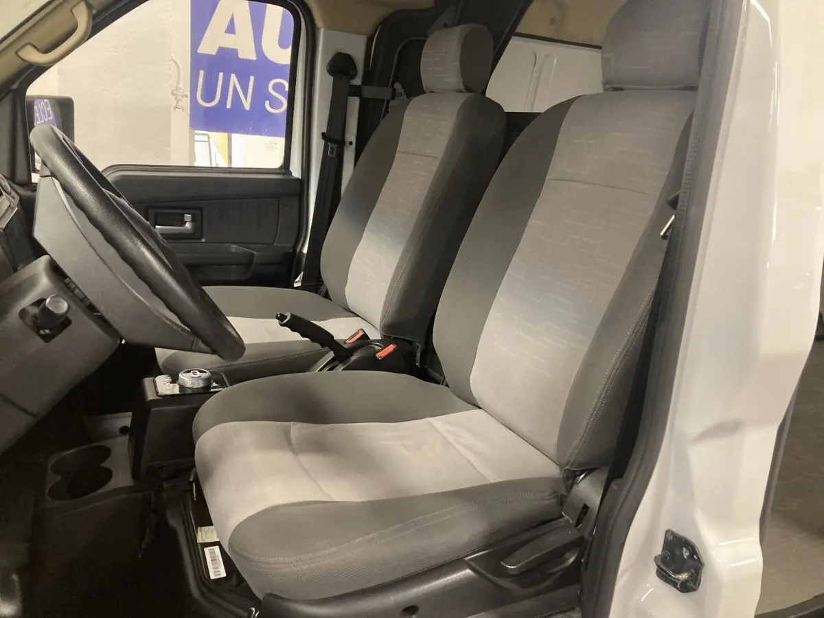 Vue intérieure côté conducteur du DFSK EC35 Ecocity 2022, montrant les sièges gris et la porte blanche ouverte.