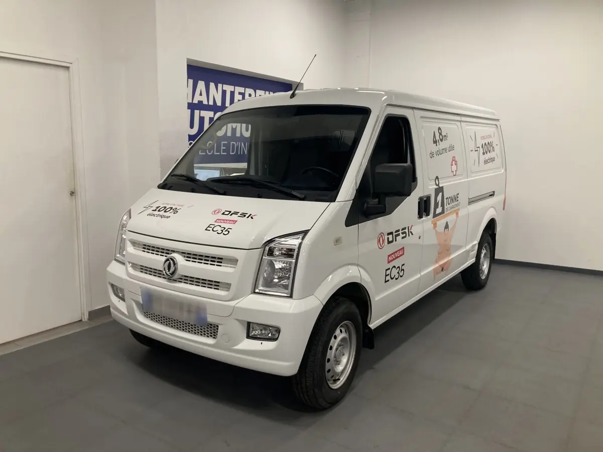 Vue 3/4 avant droit d’un utilitaire blanc DFSK EC35 Ecocity avec marquages publicitaires et logo électrique.
