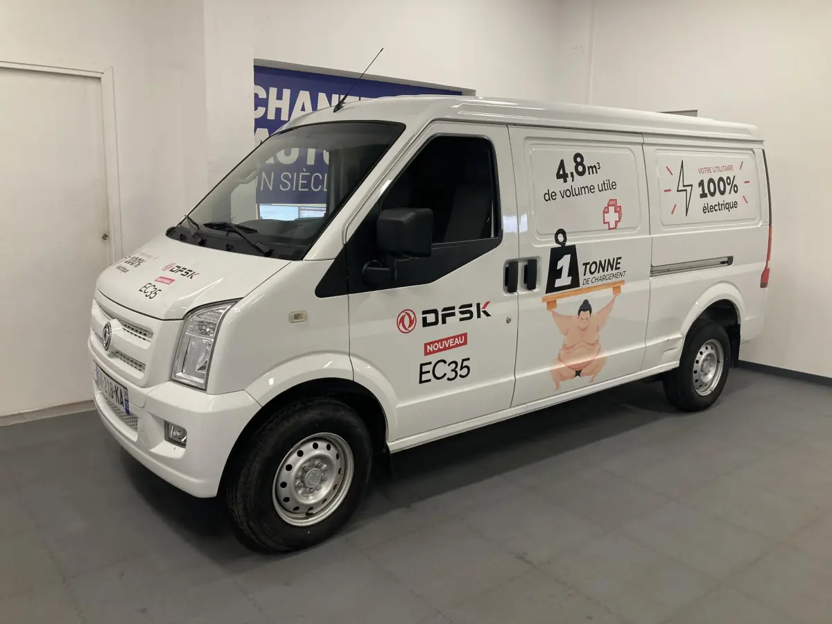 Vue 3/4 avant droit du fourgon blanc DFSK EC35 Ecocity électrique avec marquages publicitaires sur la carrosserie.
