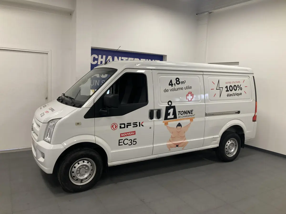 Vue de profil côté gauche d’un utilitaire blanc DFSK EC35 Ecocity 2022 avec marquages publicitaires électriques sur la carrosserie.