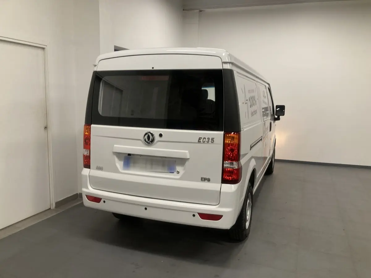 Vue 3/4 arrière d'un utilitaire blanc DFSK EC35 Ecocity électrique, avec feux arrière et logo visibles dans un garage.