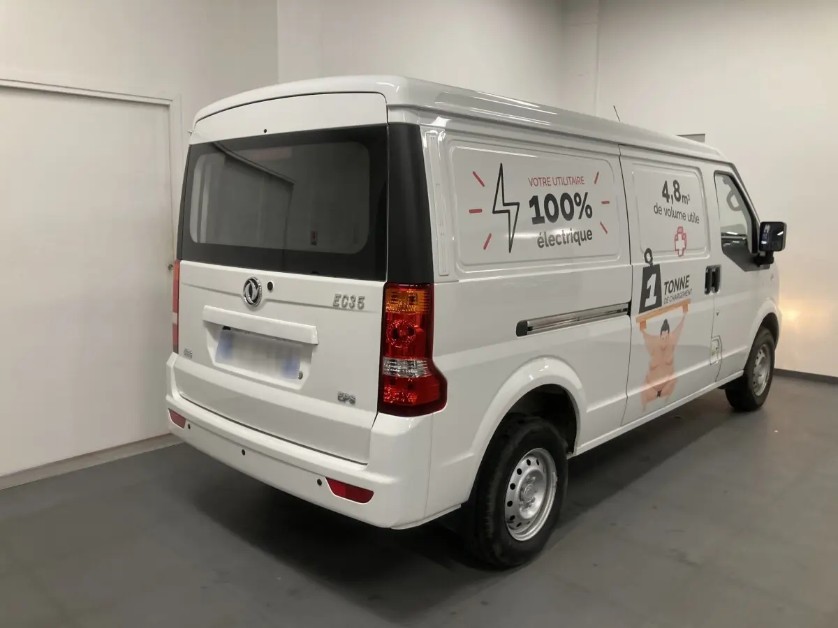Vue 3/4 arrière droite du utilitaire blanc DFSK EC35 Ecocity avec marquages publicitaires électriques sur la porte latérale.
