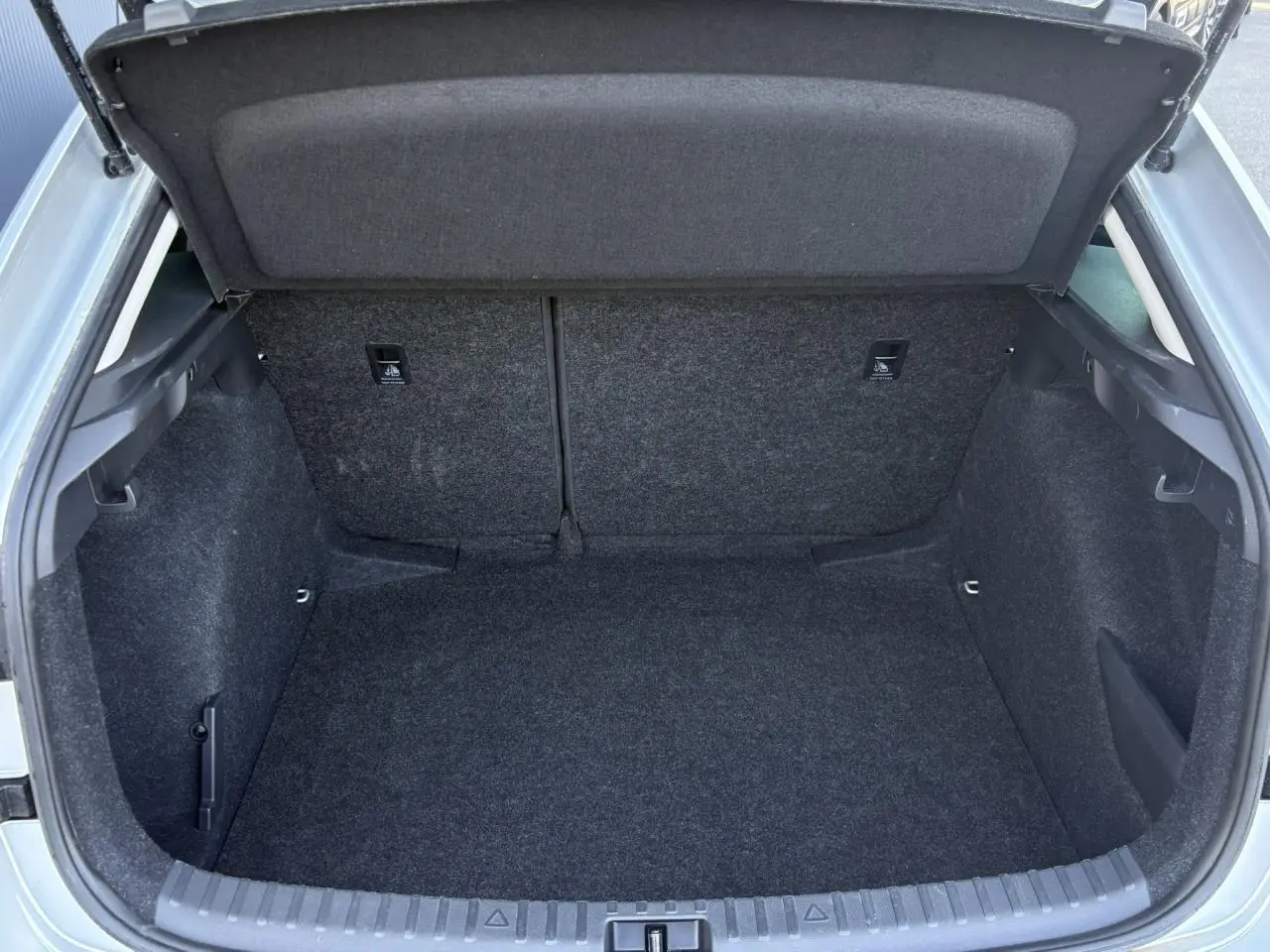 Coffre ouvert d'une Skoda Scala TSI 116 DSG7 gris Reflex, vue arrière montrant l'espace de chargement vide et tapissé.