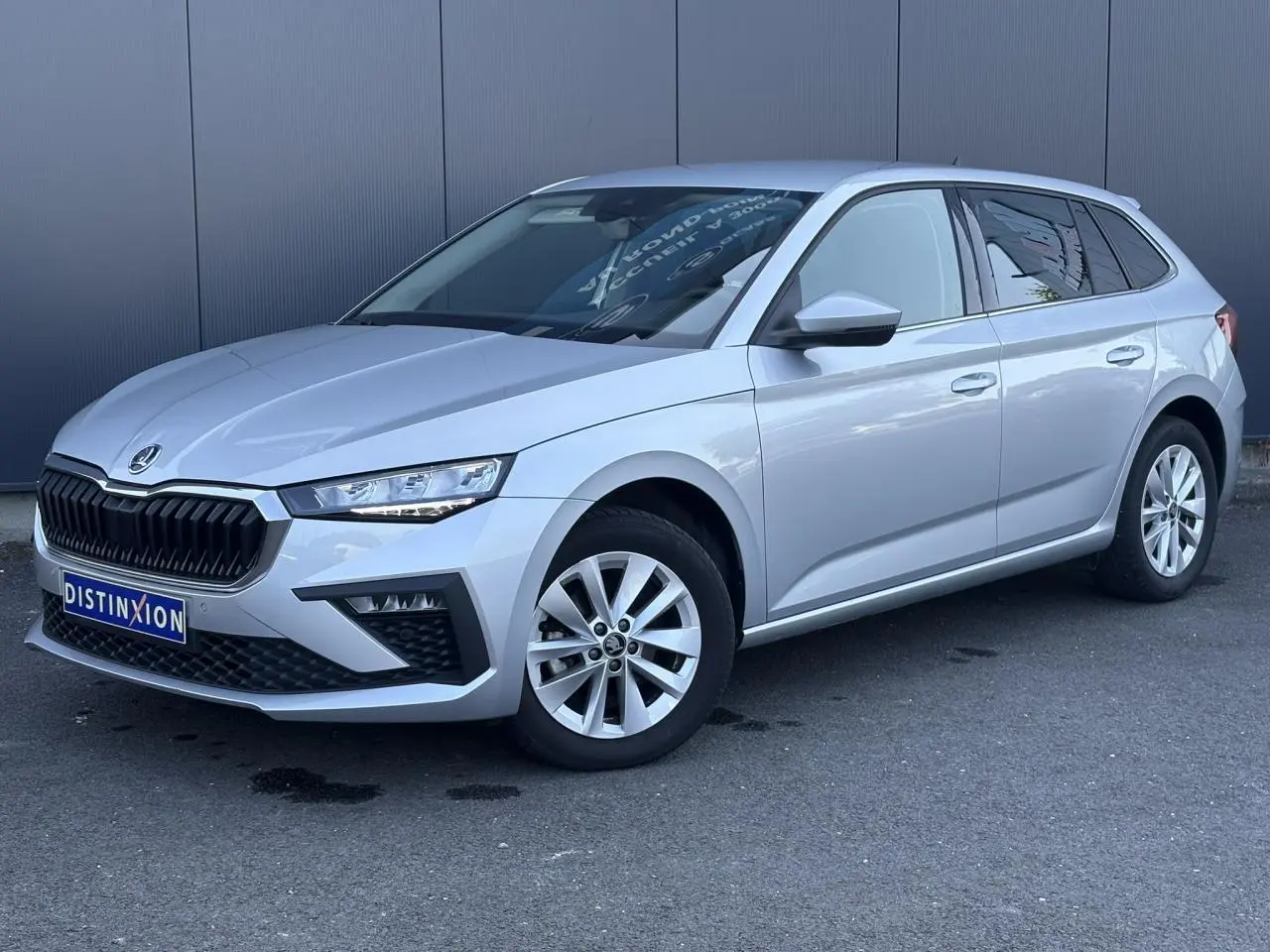Vue 3/4 avant droite d'une Skoda Scala TSI 116 DSG7 gris Reflex avec jantes alliage et calandre noire.