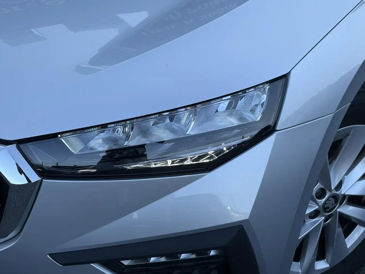 Gros plan sur le phare avant droit et la jante alliage gris Reflex d'une Skoda Scala TSI 116 DSG7 2025.