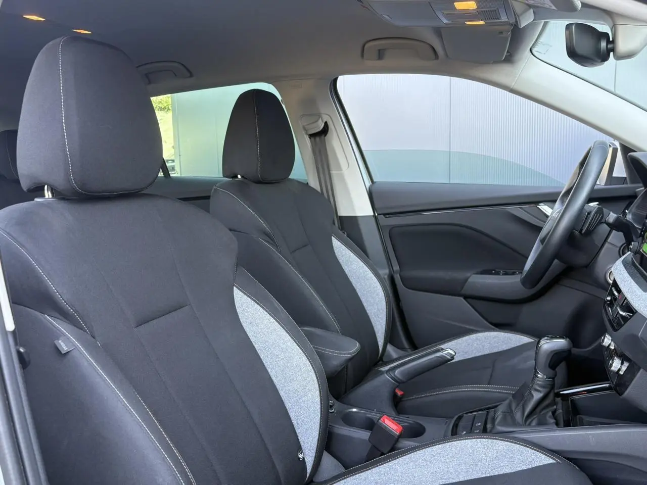 Vue intérieure côté droit de la Skoda Scala 2025, sièges tissu noir et gris avec surpiqûres blanches et console centrale.