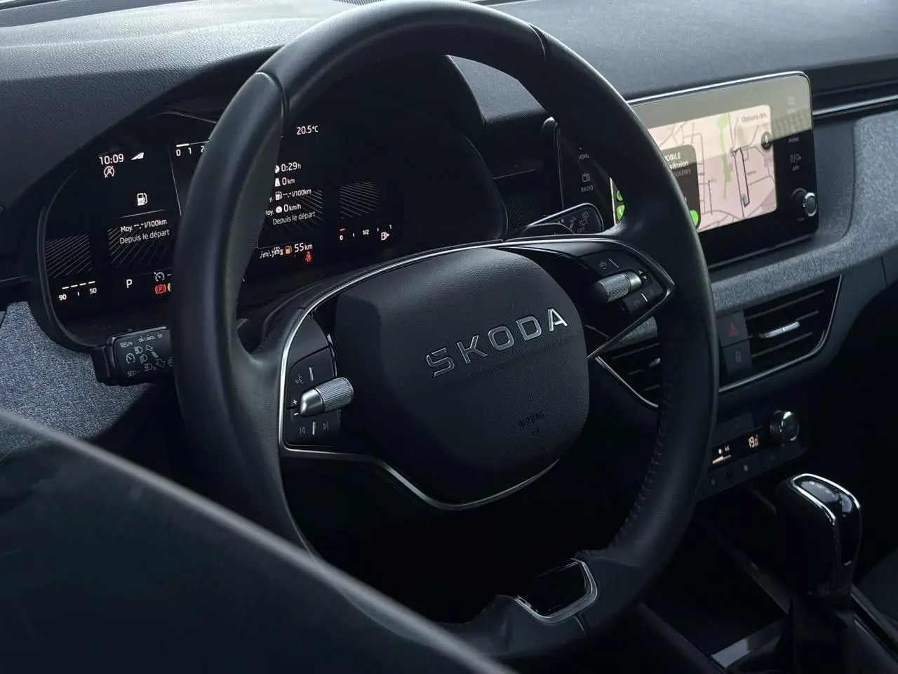 Vue rapprochée du volant noir Skoda avec tableau de bord digital et écran tactile de navigation à droite.