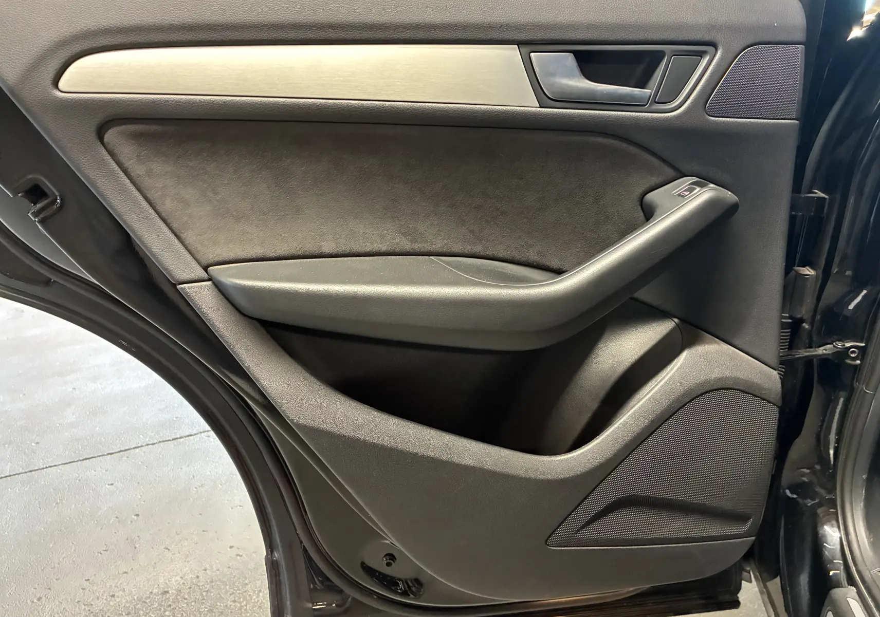 Porte arrière gauche ouverte de l'Audi SQ5 noire, avec garniture noire et insert métal brossé, haut-parleur intégré.