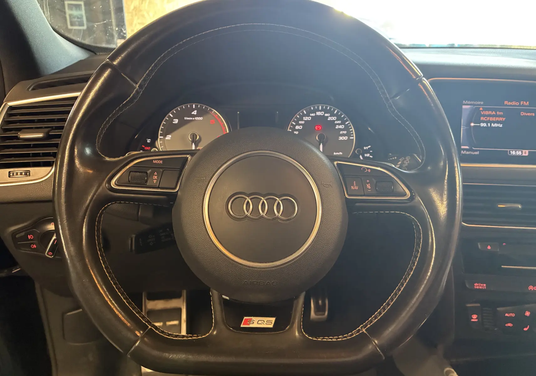 Vue rapprochée du volant cuir noir multifonctions d’Audi SQ5 avec logo S Q5 et tableau de bord visible en arrière-plan.