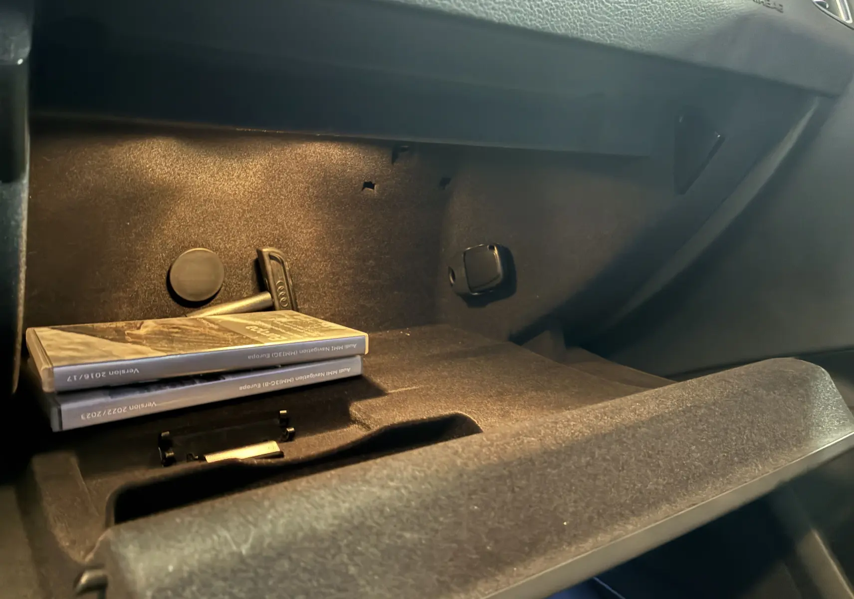 Vue intérieure du vide-poche passager de l'Audi SQ5 noir, avec manuels et éclairage ambiant doux.