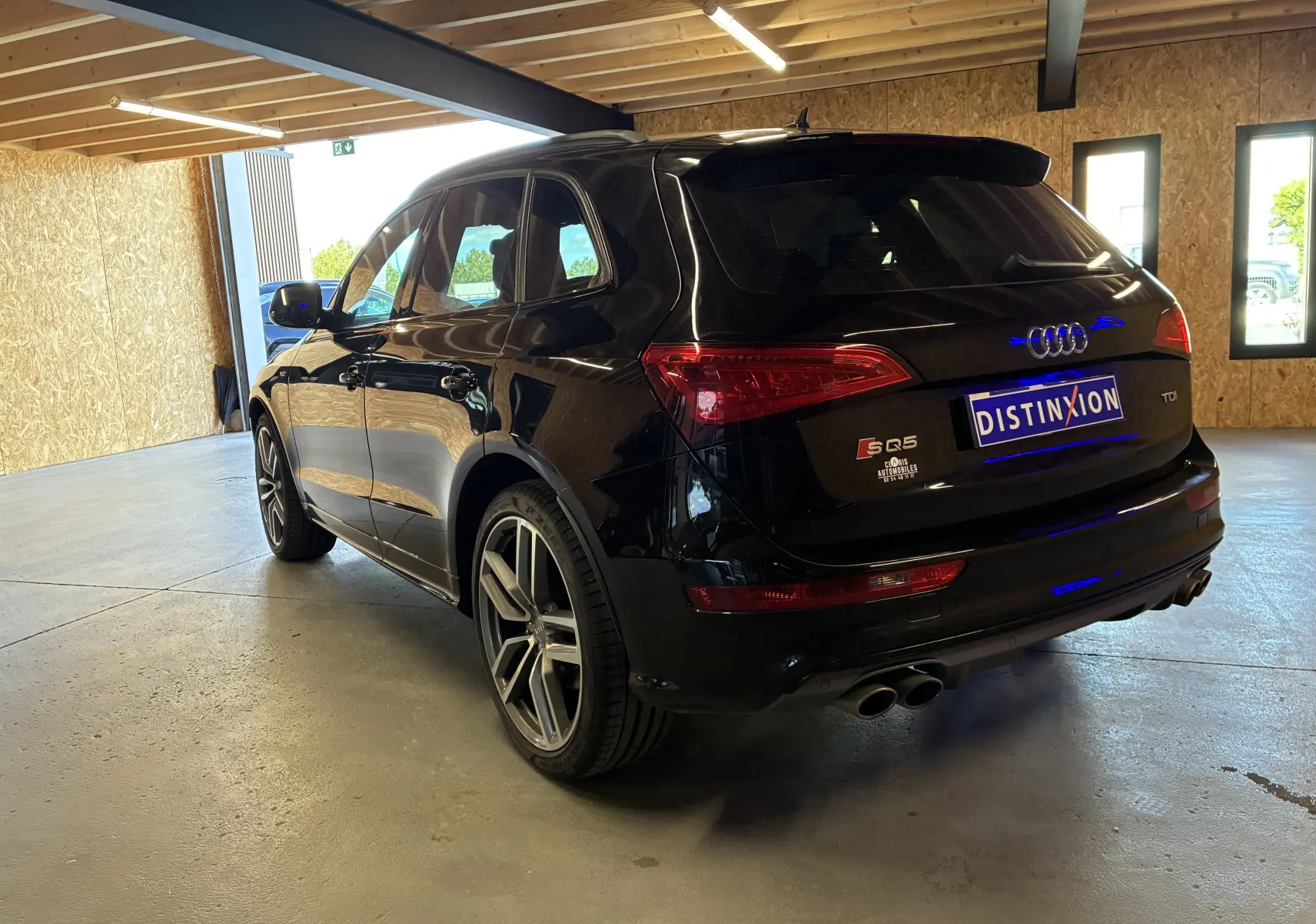 Audi SQ5 noir vue 3/4 arrière droit, avec jantes alu, double sortie d'échappement chromée et becquet arrière.
