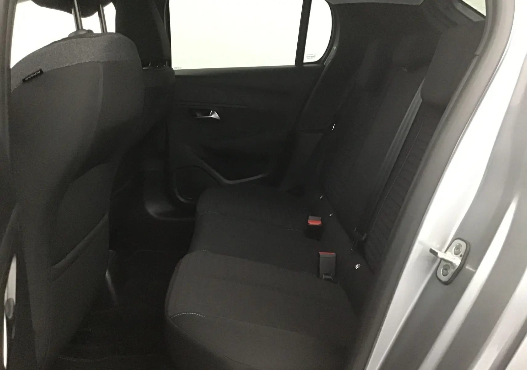 Vue intérieure côté droit sur la banquette arrière noire d'une Peugeot 208 gris Artense 2022 avec porte ouverte.