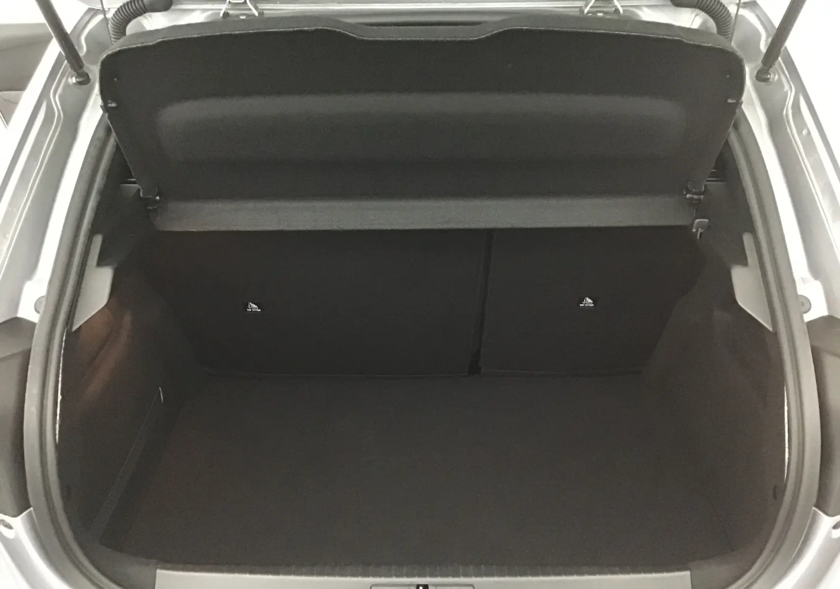 Coffre ouvert vu de dessus d'une Peugeot 208 gris Artense, montrant un espace de chargement propre et vide.