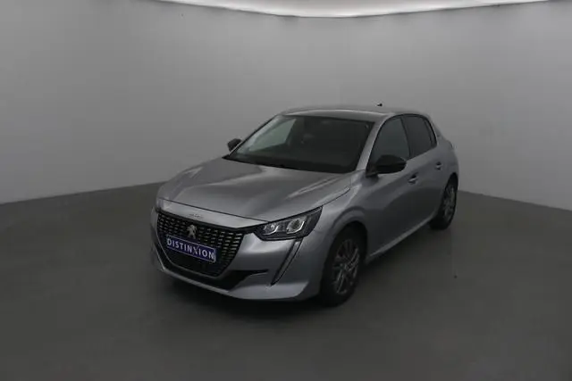 Peugeot 208 gris Artense vue 3/4 avant droit dans un studio, avec calandre noire et phares LED distinctifs.