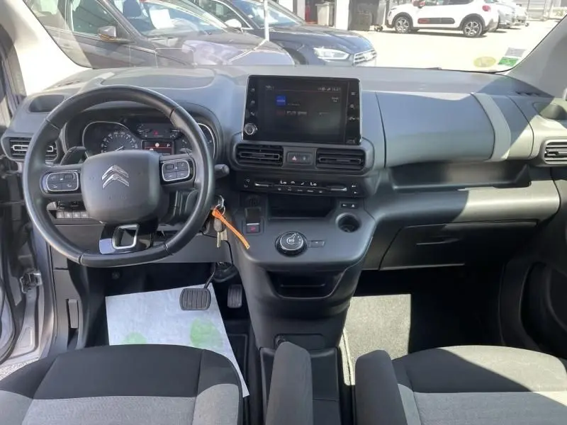 Vue intérieure avant du Citroën Berlingo gris métal 2018, tableau de bord moderne avec écran tactile central et volant multifonction.