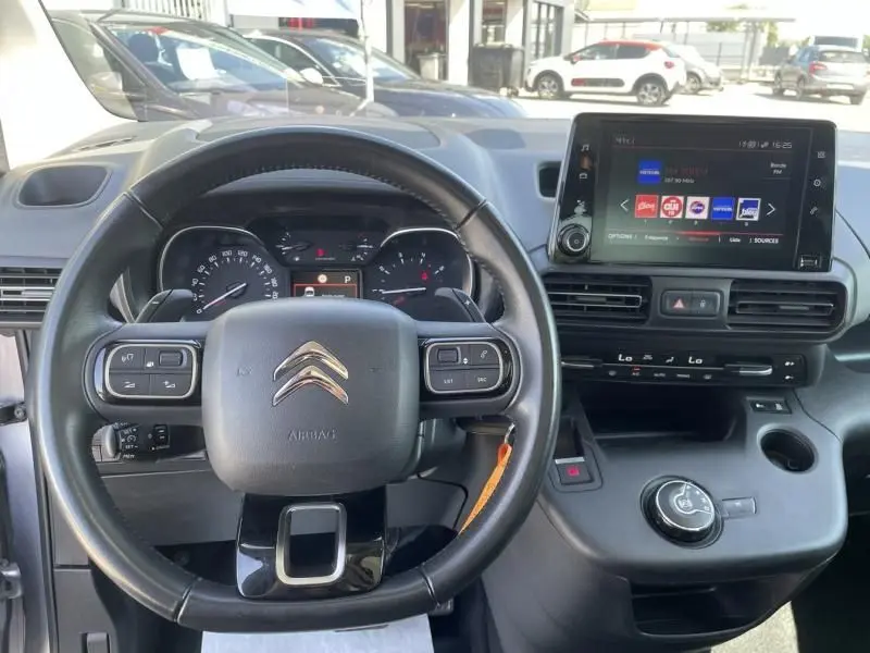 Vue intérieure du tableau de bord et volant du Citroën Berlingo gris métal 2018 avec écran tactile et commandes au volant.
