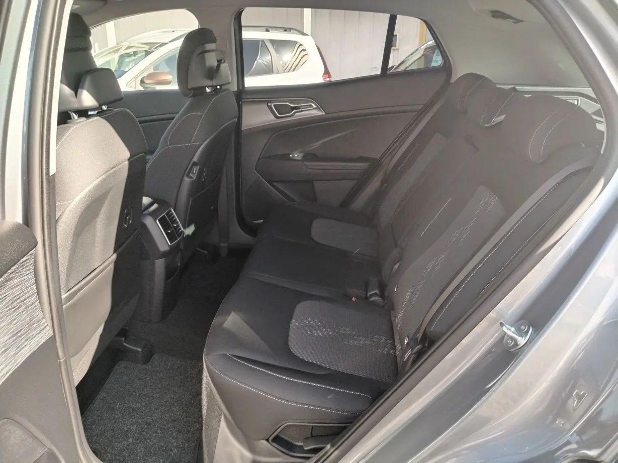 Vue intérieure côté arrière droit du Kia Sportage gris perle 2025, montrant les sièges arrière en tissu noir avec surpiqûres.