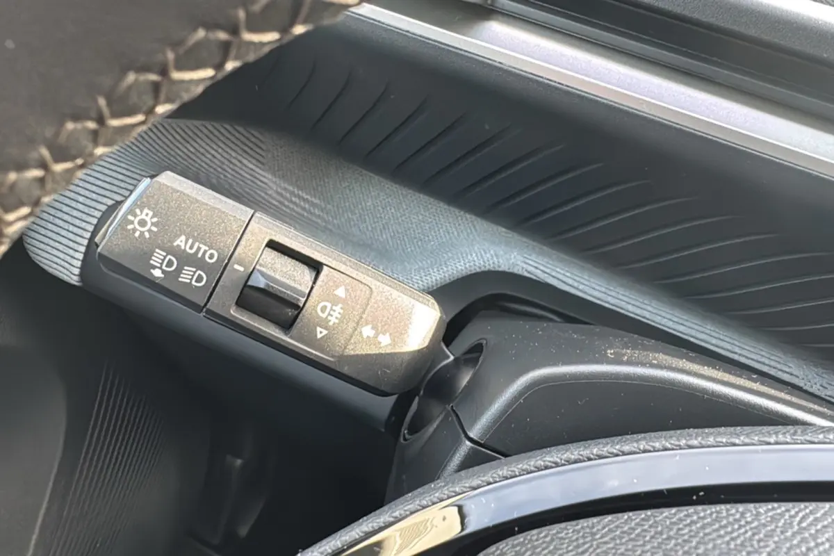 Gros plan sur la commande des feux au volant d'une Citroën C3 Aircross noir Perla Nera, version hybride 2025.