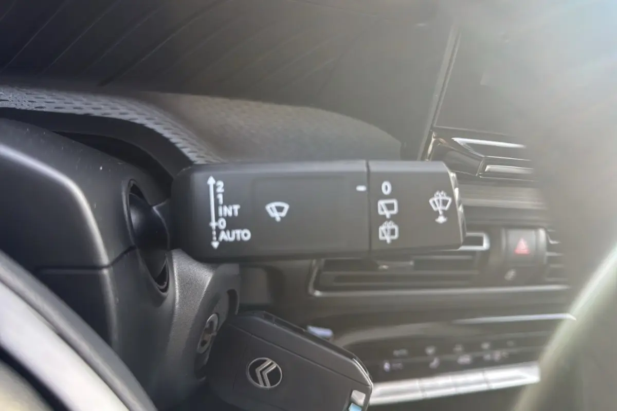 Gros plan sur la commande d'essuie-glace à gauche du volant dans l'habitacle du Citroën C3 Aircross noir perla nera.