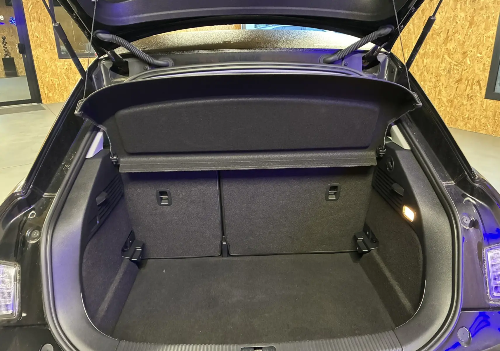 Coffre ouvert vu de l'arrière d'une Audi A1 noire 2016, montrant l'espace de chargement et la tablette cache-bagages.