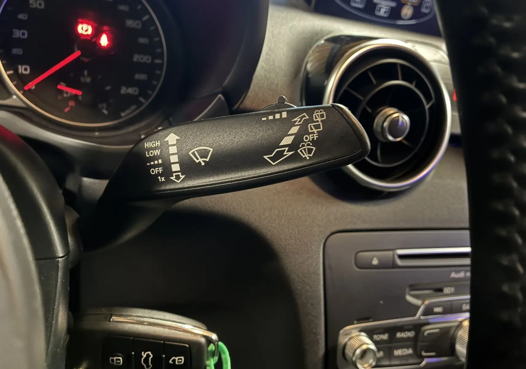 Gros plan sur la commande d’essuie-glace à gauche du volant dans l’habitacle noir d’une Audi A1 2016 S-Line.